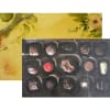 Rectangular gift box of assorted chocolates with a yellow floral lid and gold ribbon.