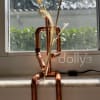 Copper pipe figure with a light bulb head and palm-like leaves