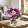 Soft blush roses meet vibrant purple carnations in a charming bouquet that