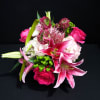 Small green berry accents and magenta-toned specialty blooms give the design a