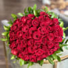 Round bouquet of red roses with green leaves