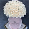 Cream roses arranged in a pink hat box with ribbon handles
