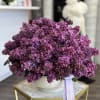 Purple lilac bouquet in a white vase with a ribbon
