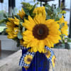 Sunflowers arranged in a blue vase with gingham bow