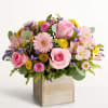 Pink roses and mixed flowers arranged in a wooden box