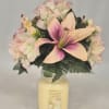 Pink and cream flowers arranged in a glass candle jar
