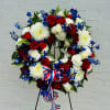 Red, white, and blue floral wreath on a stand with ribbon