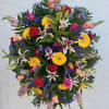 Large standing floral spray with mixed bright flowers on a black easel