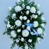 White floral standing spray with roses, chrysanthemums, and a blue ribbon