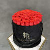 Round box filled with red roses and a black ribbon.