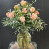 A dozen gorgeous peach roses arranged in a vase.