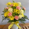 Bouquet of yellow and pink flowers in a white vase with a yellow ribbon
