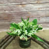 White lily of the valley arrangement in a dark green container