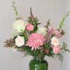 Pink and white mixed flower arrangement in a green glass vase