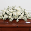 Large all-white casket spray of white roses and delicate filler flowers, draping
