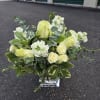 White and pale yellow floral arrangement in a clear square vase