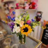 Mixed bouquet in a clear glass vase with a sunflower, roses, and lilies
