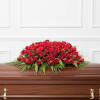 Dense, low mound of red roses with fern-like greenery edges.