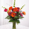 This vase arrangement contains sun-like orange and pink gerberas, bells of Ireland