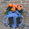 Peach-orange flowers in a dark planter with a large blue ribbon