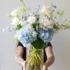 A soft, garden-inspired arrangement in calming blue and ivory tones, featuring lush