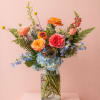 A vibrant, garden-style arrangement filled with layered seasonal blooms in soft pastels