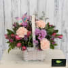 Soft peach, pink and lavender blooms spill from a white woven basket