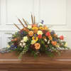 Large, low casket spray of warm roses, daisies, carnations and mums with