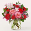 Pink roses and red carnations in a clear glass vase