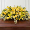 Large, low casket spray with yellow roses, yellow lilies and white fillers