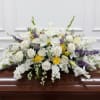 Large, low casket spray of white roses and lilies with yellow and