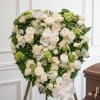 Large heart-shaped standing tribute of tightly packed white roses, orchids and pale