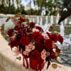 A lush cluster of red and blush roses-accented with spray roses and