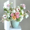 A garden-style bouquet of blush pink, peach and white blooms that feels