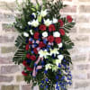 Standing floral spray with red, white, and blue flowers and ribbon