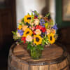 Bright yellow sunflowers take center stage in this cheerful flower arrangement, a