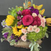 Bright mixed bouquet with roses, sunflowers, lilies, and hydrangea in a wooden base