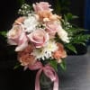 Soft pink roses and peach-and-white carnations mingle with tiny white daisy-like blooms