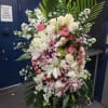 A tall, graceful standing spray of soft pink roses, white lilies, and