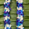 Purple, blue, and white flower lei on a green leaf background