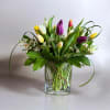 Mixed tulip bouquet in a clear glass vase with white filler flowers