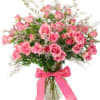 Arrangement of pink roses and filler flowers in a clear glass vase with a pink ribbon bow