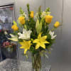 Yellow roses and white lilies in a clear glass vase