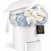 Pale blue hydrangeas, white roses, and delicate white Phalaenopsis orchids spill from