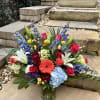 Colorful mixed bouquet in a glass vase with lilies, roses, hydrangea, and blue delphinium