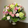 Mixed pink and white floral arrangement in a silver pedestal vase
