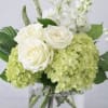 White roses and pale green hydrangeas in a clear glass vase