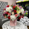 Bouquet of red, pink, and white flowers in a pink hatbox