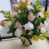 Basket arrangement of pale pink roses, white carnations, and yellow filler flowers