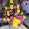 Basket arrangement of yellow roses and purple daisies